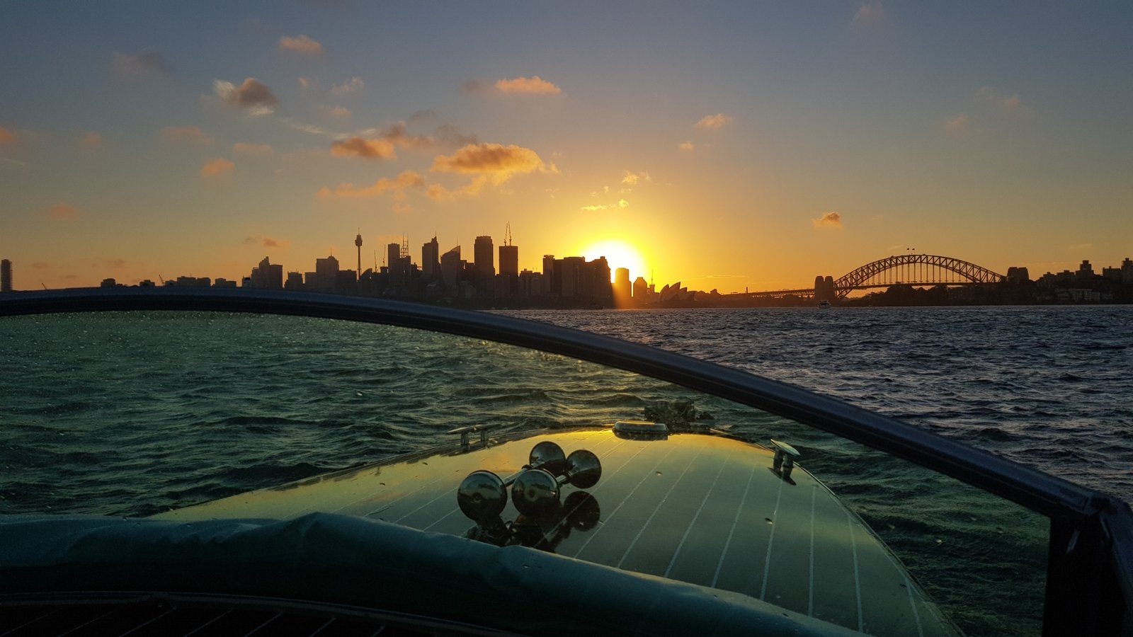 Sunset over Sydney Harbour with city skyline and Sydney Harbour Bridge visible, taken from Venetian-style romantic MV Bel