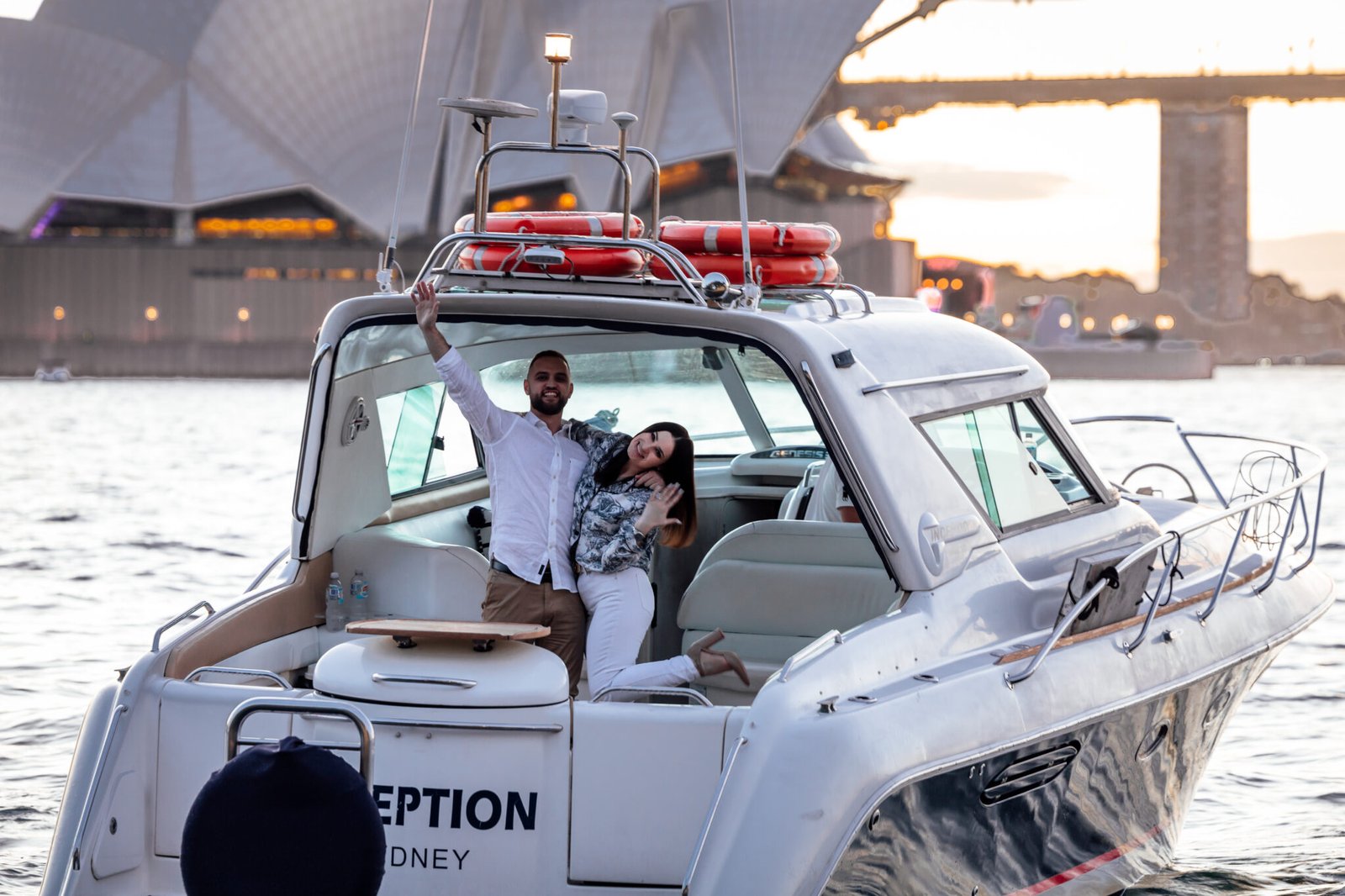 Couple seated on yacht as woman shows engagement ring during Sydney Harbour cruise.