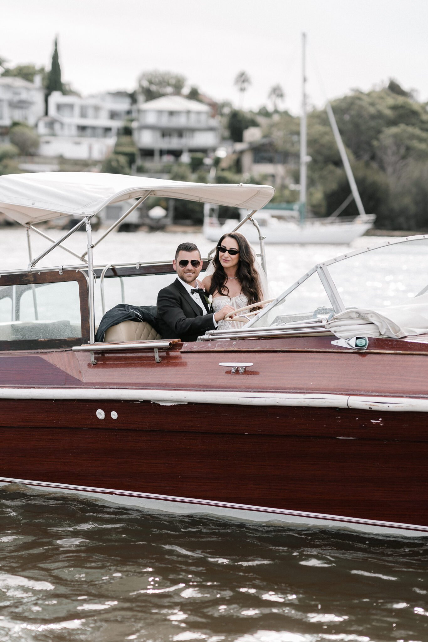 Wooden wedding yacht sailing past a lighthouse on Sydney Harbour.