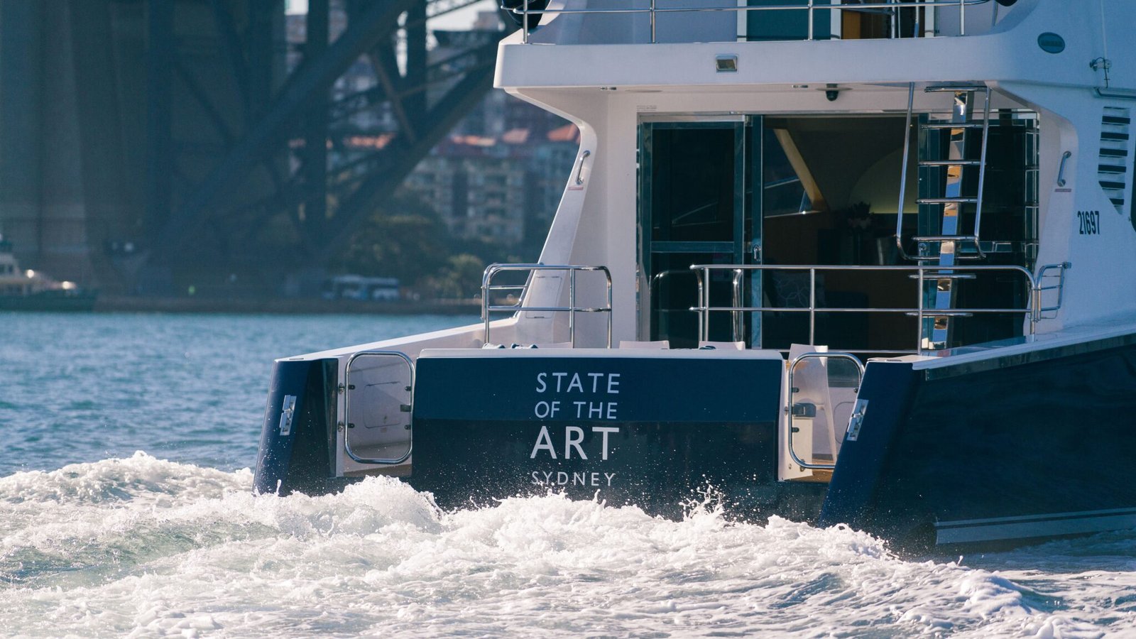 Modern catamaran MV State of Art cruising past Sydney skyline.