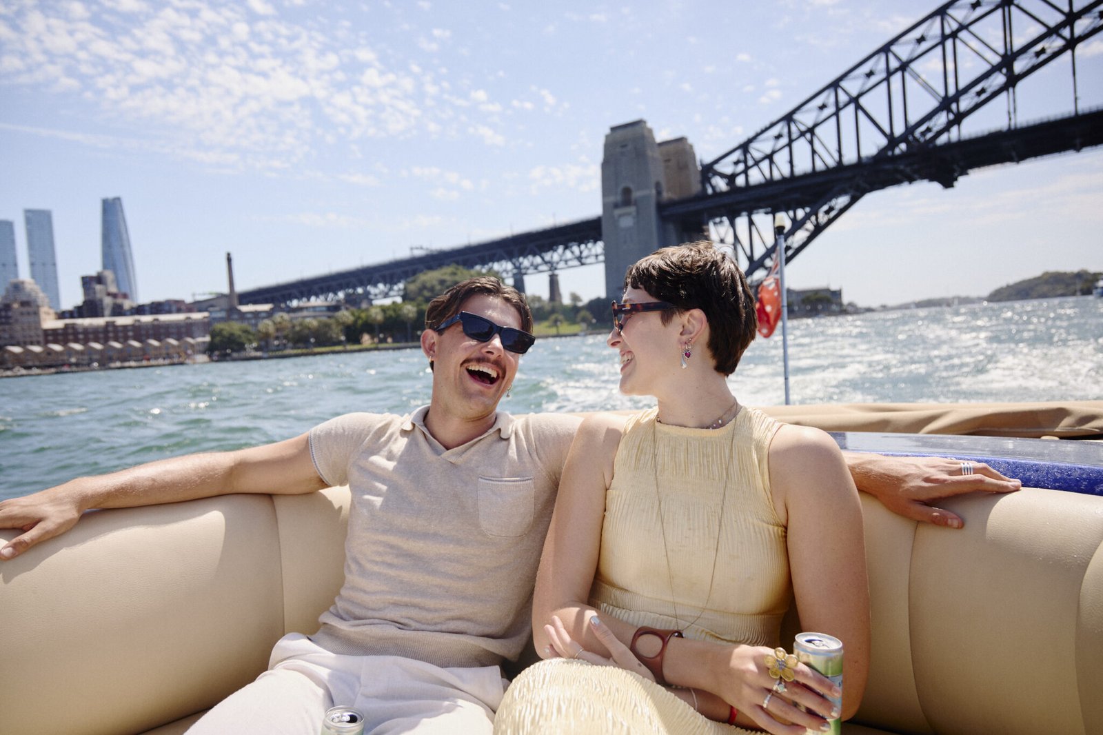 Couple laughing together aboard MV Aquamajestic with Sydney Harbour Bridge behind.