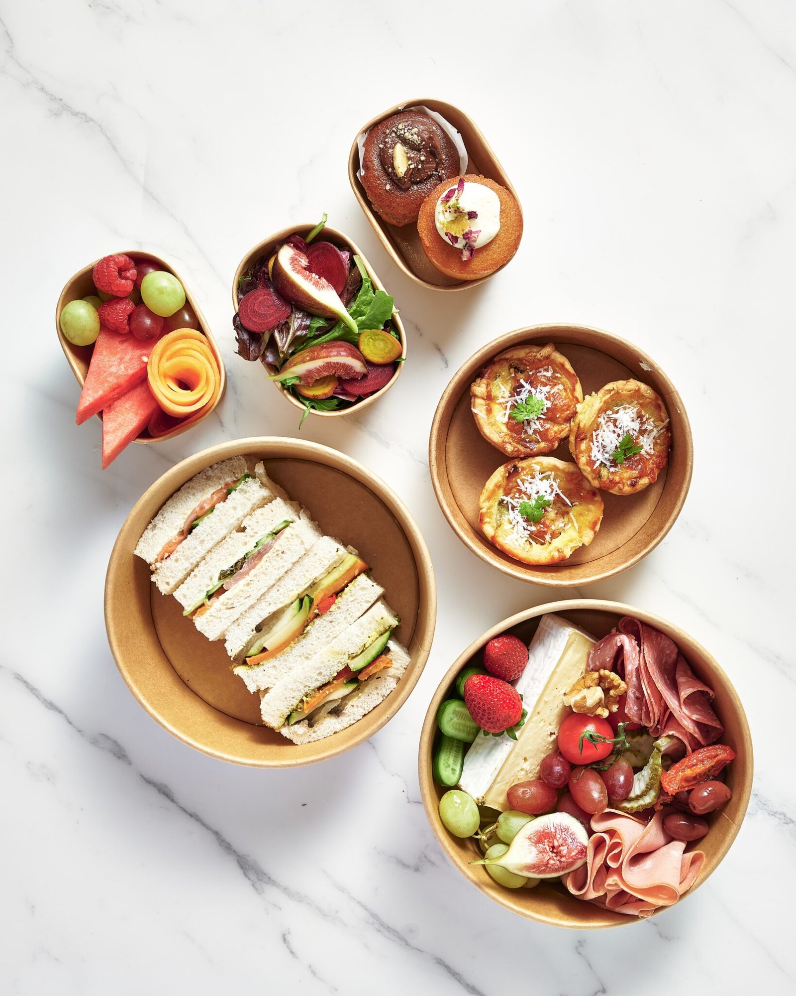 Lunch spread with grazing platter, charcuterie, quiches, sandwiches, salads, and desserts.